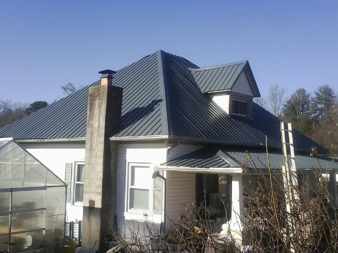 Dark blue standing seam metal roof on a white farmhouse with dormer — Slate & Tile Roof Repair by Roofing Brothers in Ambler