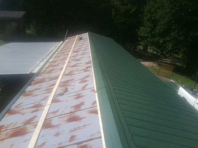 Old rusted panels beside newly installed green metal roofing — Wind Damage Roof Repair by Roofing Brothers in Ambler