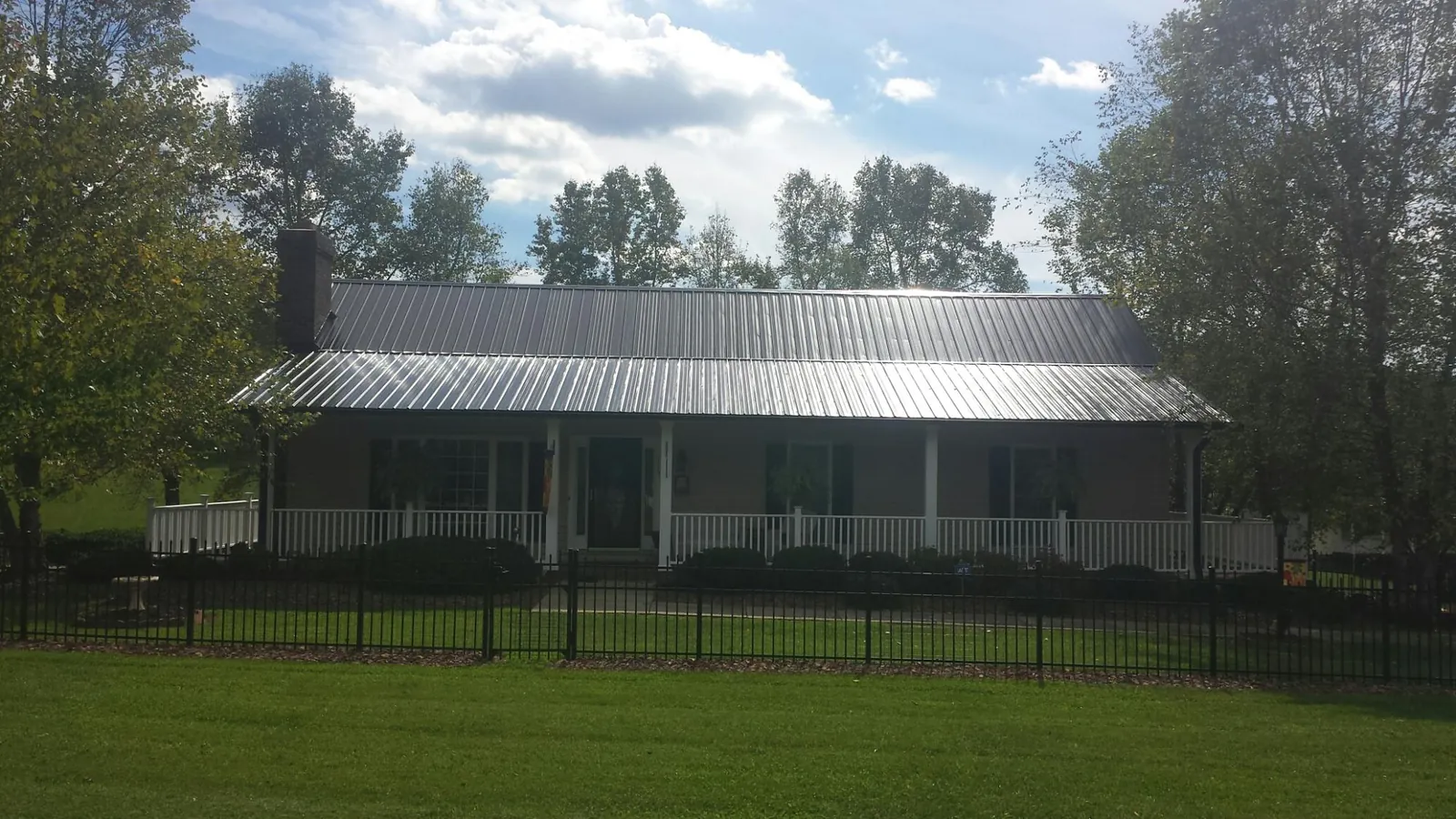 Gray metal roof on a brick ranch with a full width front porch — Gutter Guard Installation work by our crew in Ambler