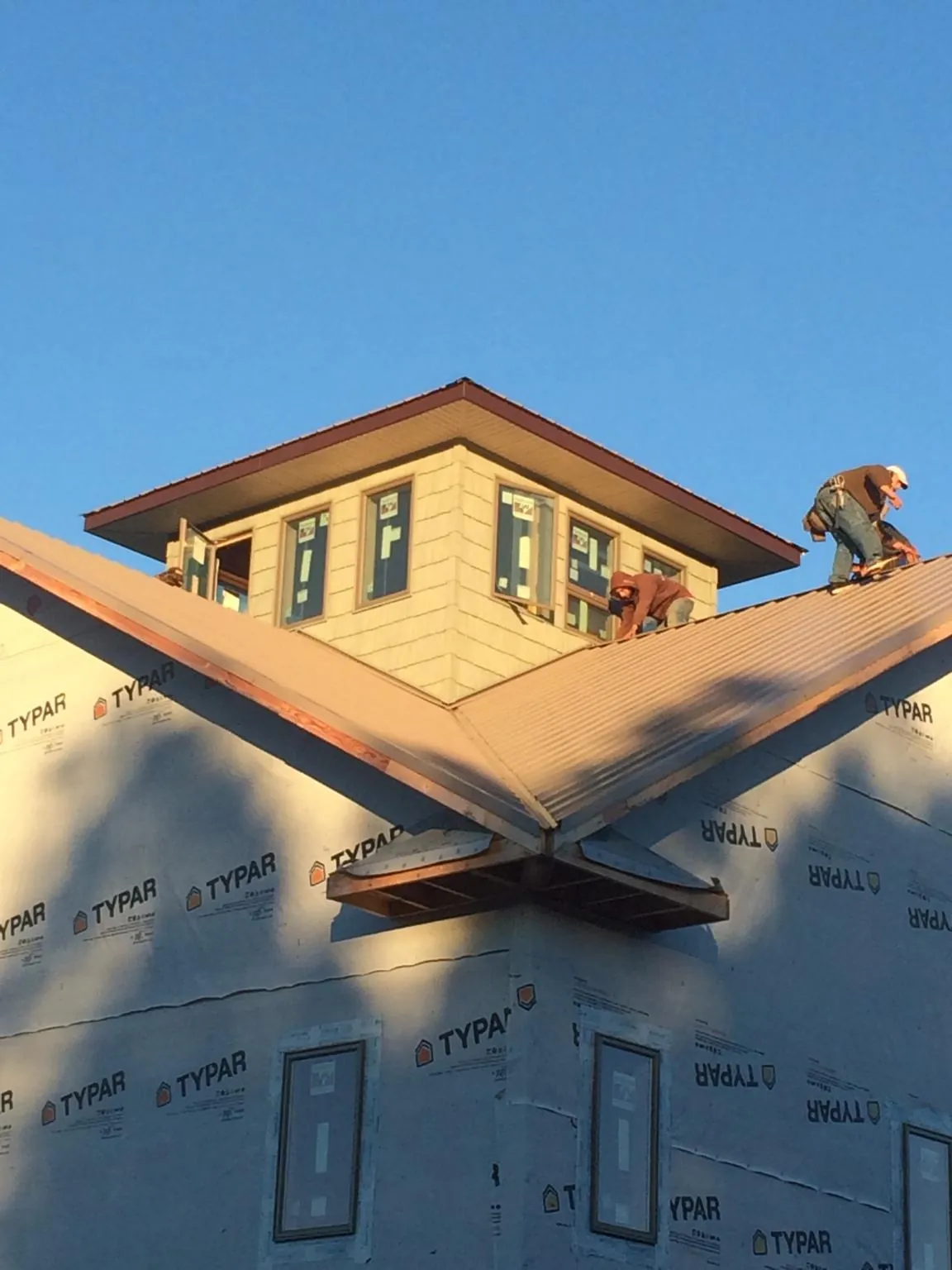 Roofers working around a rooftop cupola on a new metal roof at sunset — Roof Waterproofing in Ambler by Roofing Brothers